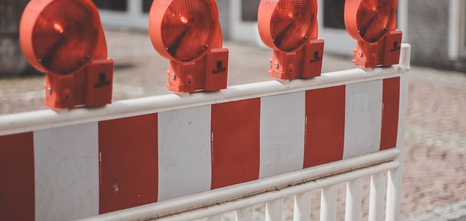 Eine rot-weiße Warnbarke weist auf eine Baustelle hin.