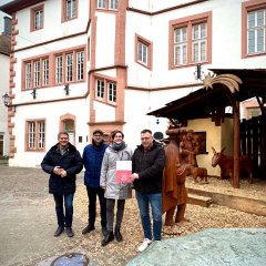 Fünf Personen stehen vor der großen Weihnachtskrippe auf dem Alzeyer Fischmarkt