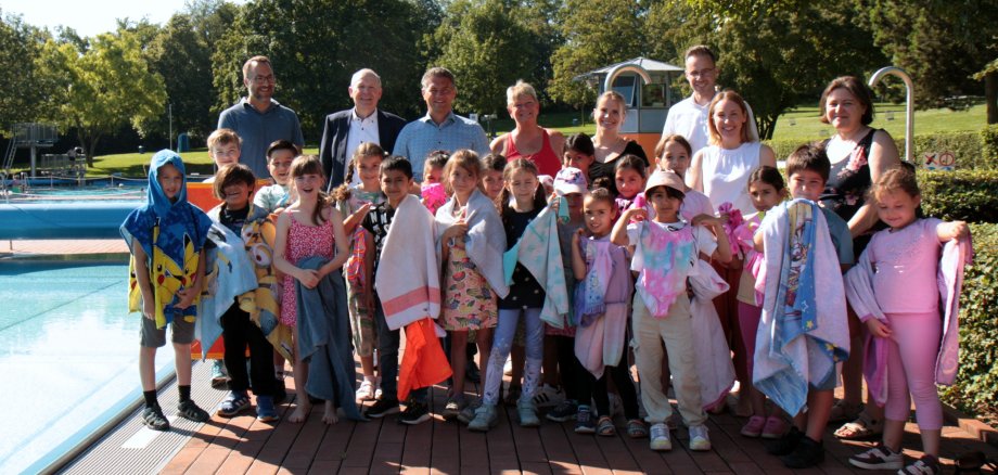 Die Kinder der Nibelungenschule mit Vertretern des Rotary Clubs Alzey stehen am Beckenrand des Schwimmerbeckens im Alzeyer Wartbergbad