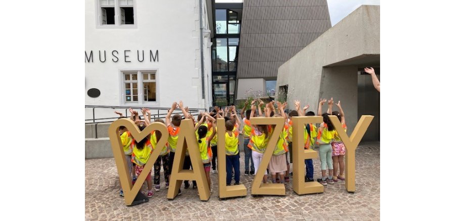 Kinder stehen mit erhobenen Händen hinter dem Alzey Logo am Alzeyer Museum