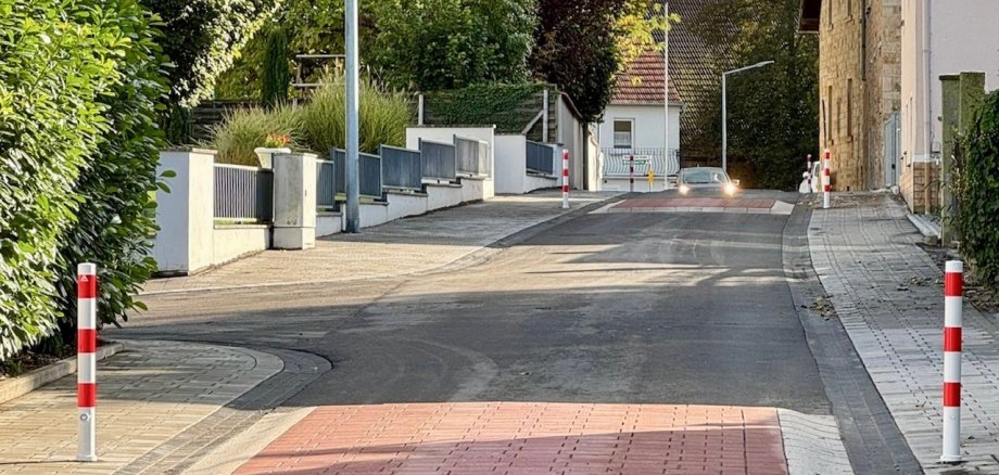 Zwei rote Erhebungen im Verlauf einer Straße. Im Hintergrund fährt ein Auto auf den Hubbel zu.