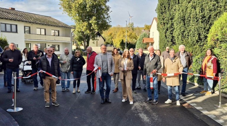 Viele Menschen schneiden ein über eine Straße gespanntes Band durch.