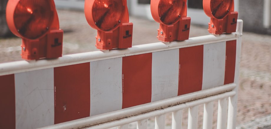 Eine rot-weiß gestreifte Absperrung mit orangenen Leuchten