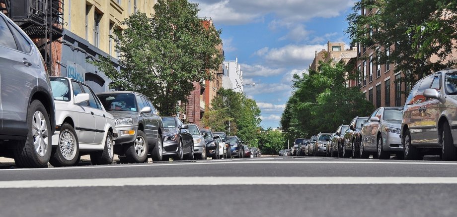 Eine Straße, an deren Rändern zahlreiche Fahrzeuge parken.