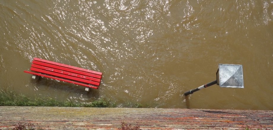 Eine Bank und eine Laterne stehen unter Wasser